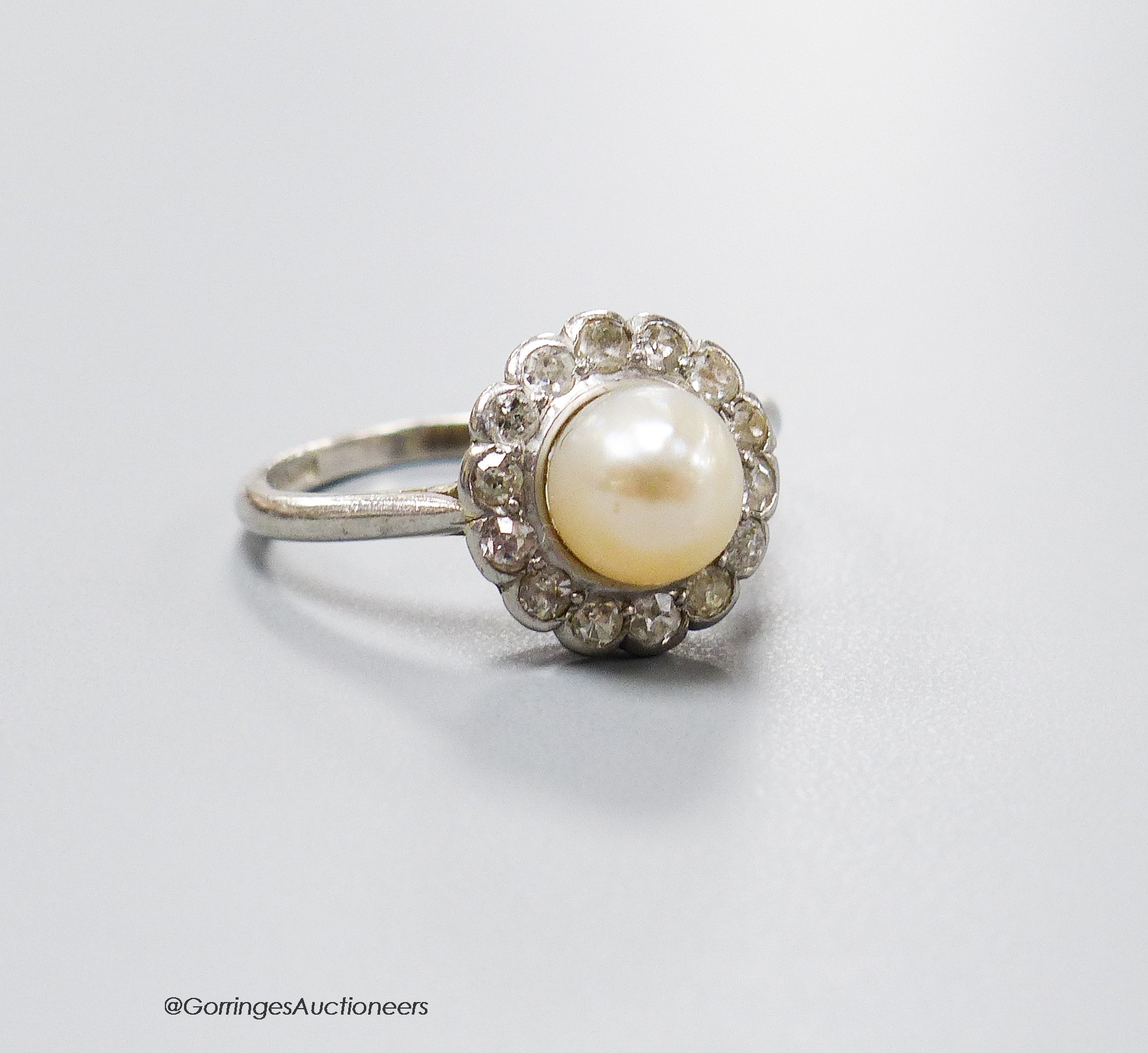 A 1920's white metal (stamped platinum), cultured pearl and old cut diamond set circular cluster ring, size M/N, gross weight 4.4 grams.